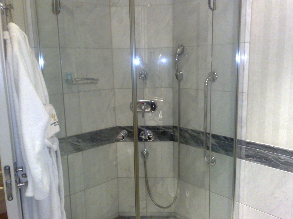 A walk-in glass shower with marble-look tiles and a polished chrome shower set